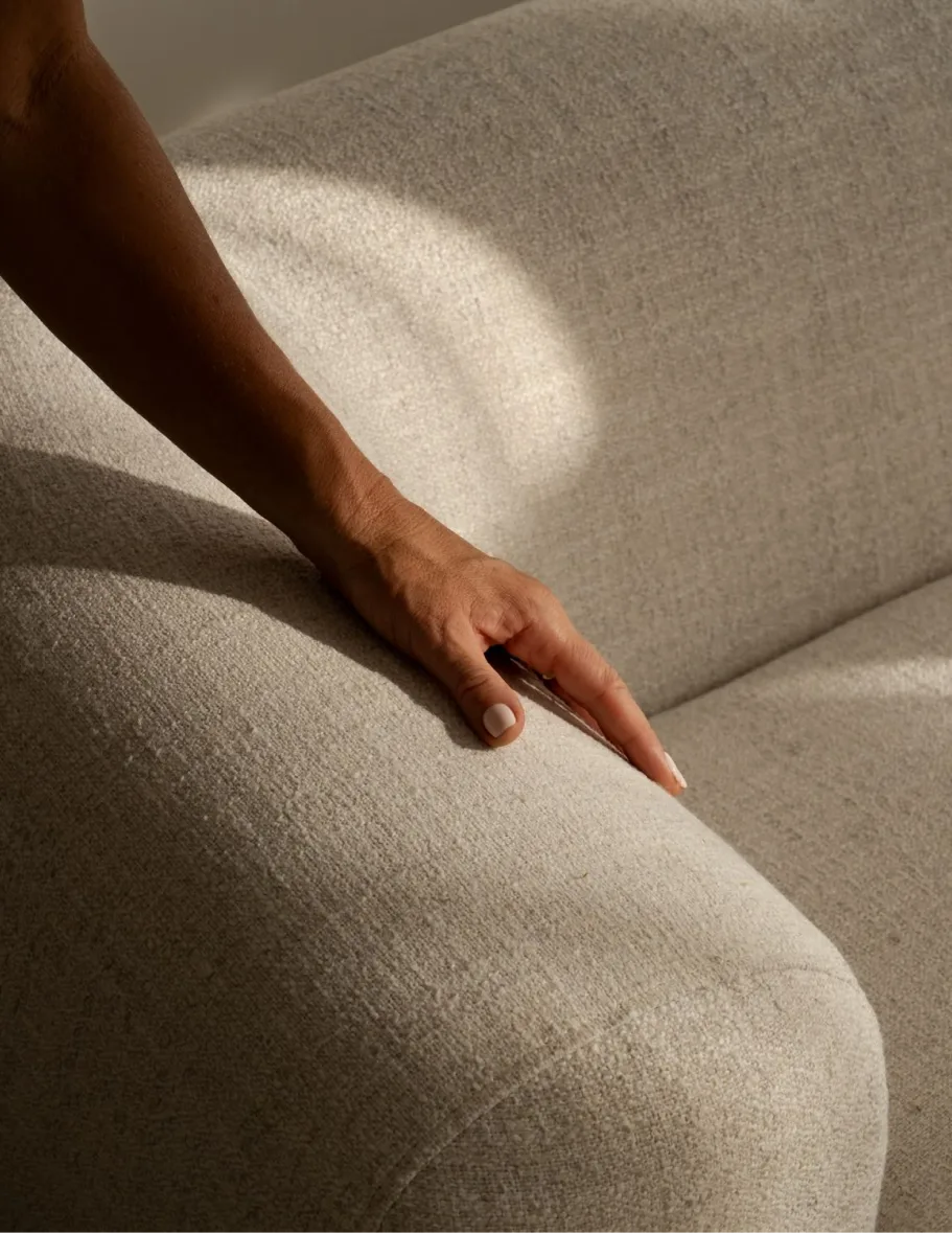 Hand resting on a linen sofa in warm light